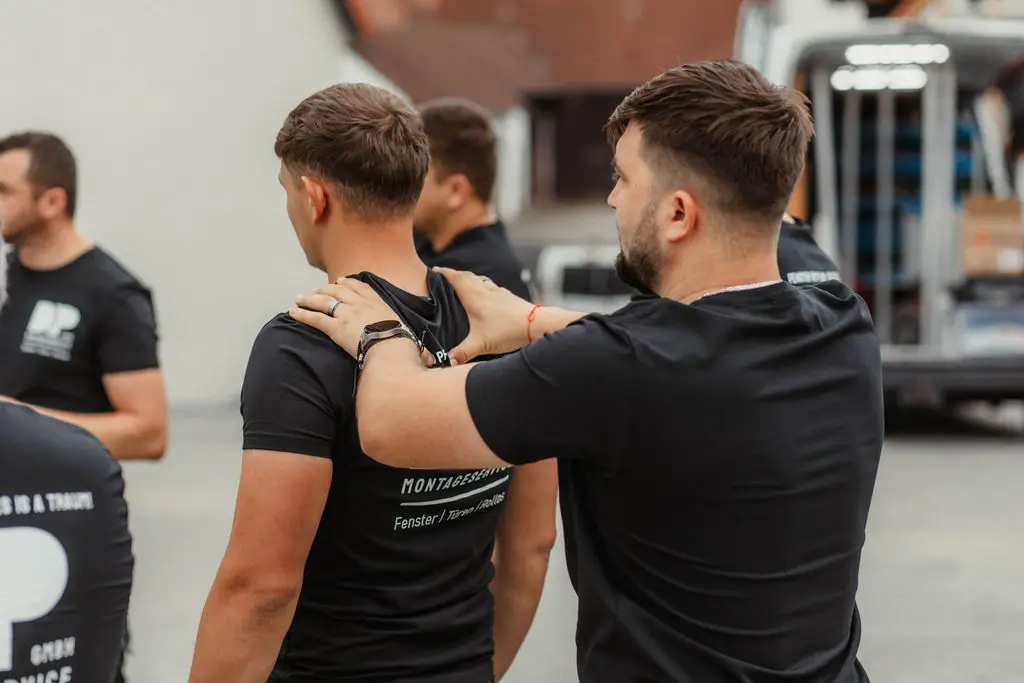 Teambesprechung bei DP: Ein Kollege gibt dem anderen eine scherzhafte Massage