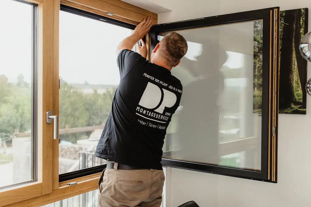 Daniel Pflaum passt das Fliegengitter nach Maß in den Fensterrahmen ein