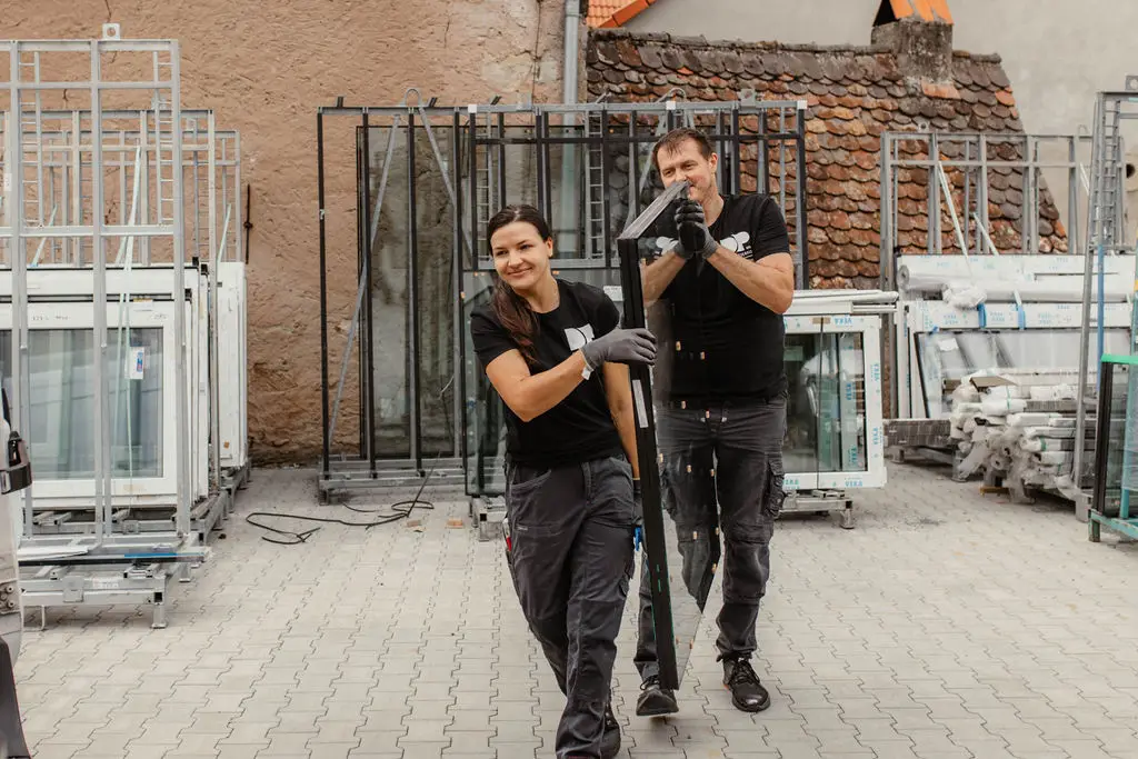 DP Montageservice Team trägt ein Fenster über den Hof